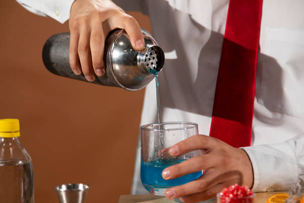 barman prepara una bevanda alcolica con uno shaker al bar con alcuni bicchieri di liquore. - shakerismo foto e immagini stock