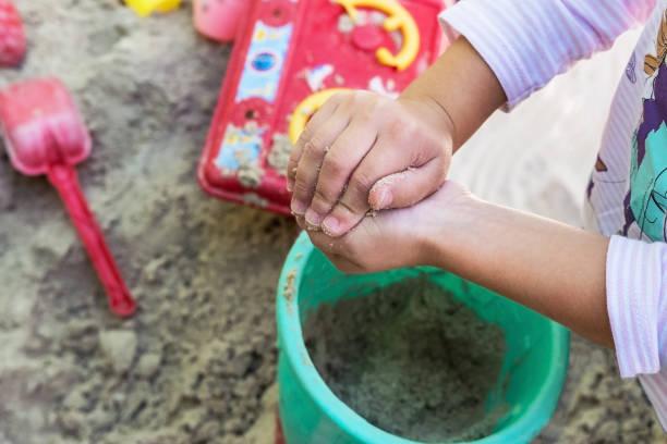 Child's hand close up playing kinetic sand at home indoors.