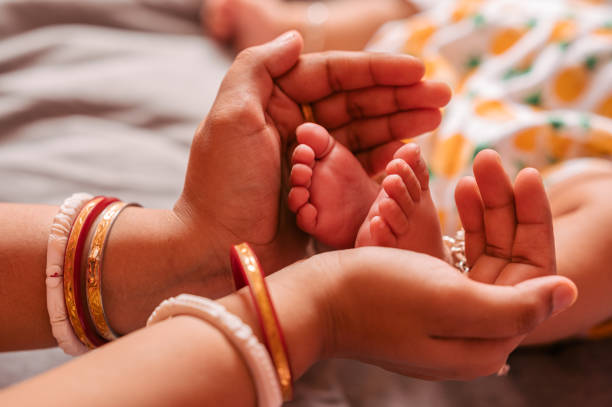 Close up Mother Holding Feet of Baby in Her Hand Close up Mother Holding Feet of infant Baby in Her Hand, Baby feet in mother hands. Tiny Newborn Baby's feet on female Shaped hands closeup. indian boy barefoot stock pictures, royalty-free photos & images