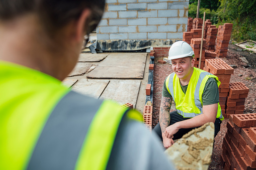A close-up shot of a Caucasian male construction worker having a conversation with a colleague onsite.