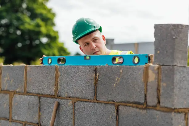 A shot of a spirit level being used to check some brickwork by a caucasian male construction worker.