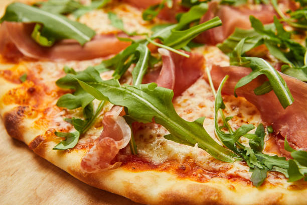 istock Delicious Italian Pizza with Parma ham and arugula, mozzarella cheese on dark background 1273025100