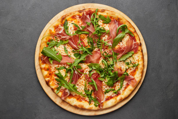 istock Delicious Italian Pizza with Parma ham and arugula, mozzarella cheese on dark background 1273029110