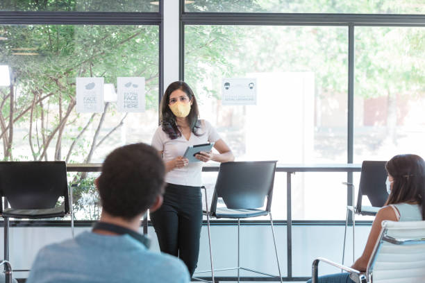 istock Female team lead gives presentation while wearing protective mask 1273035439