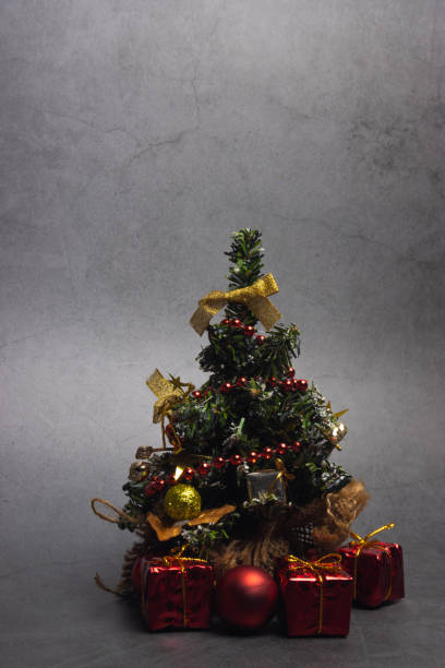 istock Vertical orientation. Small Christmas tree with presents and New Year's red decorations on a dark background. 1273039172