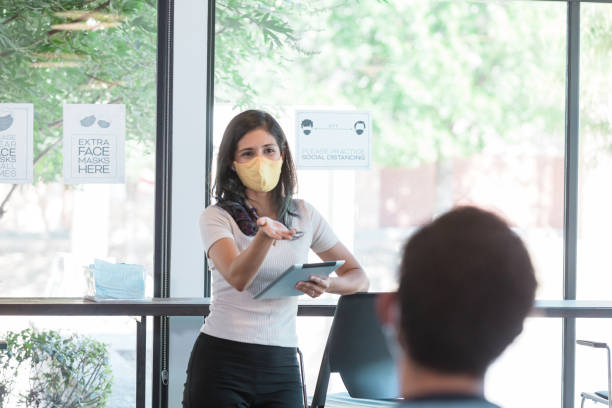 istock Woman with mask gestures toward unrecognizable colleague 1273039661