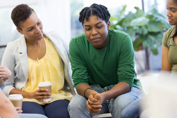 Mom encourages teen as he shares in therapy group The mid adult mom encourages her teenage son as he gets the courage to speak out in therapy group. serious black teen stock pictures, royalty-free photos & images