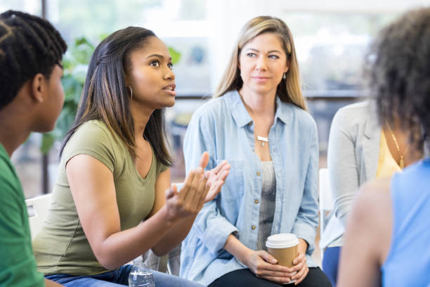 Everybody in therapy group looks at teen girl As the teen girl gestures and expresses strong emotion, everybody looks to her. group therapy stock pictures, royalty-free photos & images