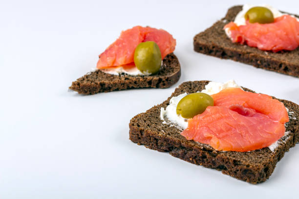 Appetizer, open sandwich with salmon and soft cheese on white background. Traditional Italian or Scandinavian cuisine. Concept of proper nutrition and healthy eating. Flat lay, copy space for text