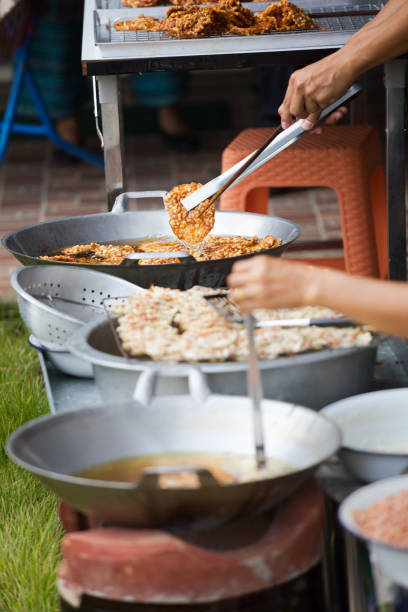 Thai women preparing thai peanut snack i oil and cauldron