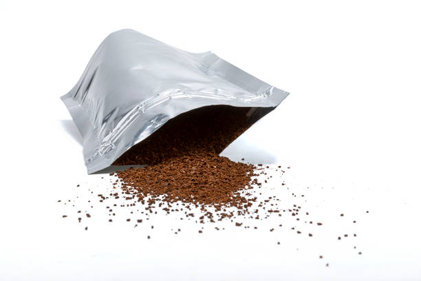 Resealable aluminum bag with brown beans coming out on white background