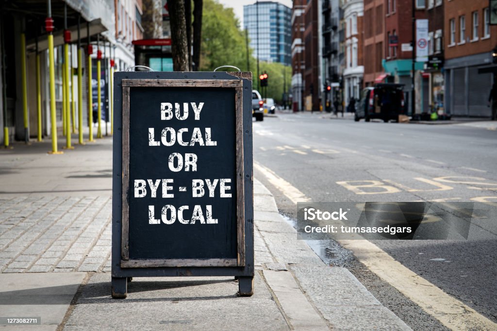 BUY LOCAL OR BYE - BYE LOCAL. Foldable advertising poster BUY LOCAL OR BYE - BYE LOCAL. Foldable advertising poster on the street Ethical Consumerism Stock Photo