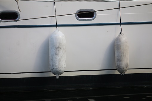 a close up of white fender hanging on the sailing boat