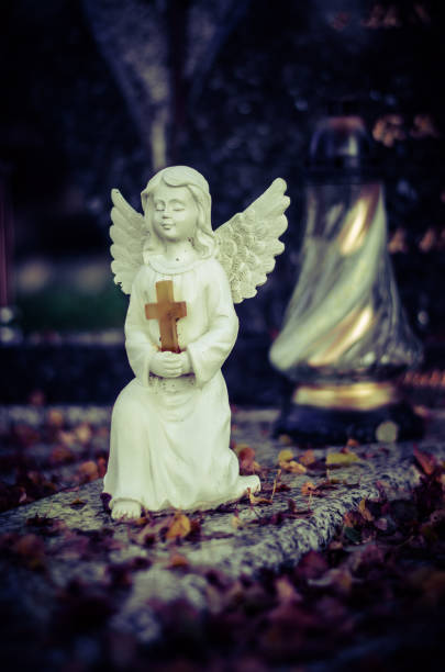 lindo anjo branco inocente bonito durante o dia de todos os santos no cemitério - angel praying statue human knee - fotografias e filmes do acervo