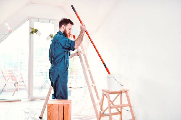 istock Handsome Male Painter Dipping Roller Into Bucket Of Paint 1273096783