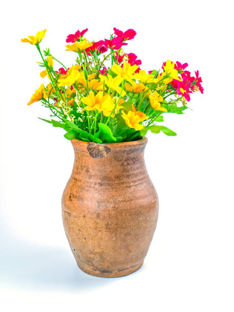 A bouquet of artificial flowers in a clay jug.