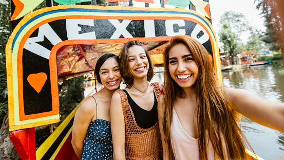 Girlfriends visiting Xochimilco in Mexico city taking a selfie.