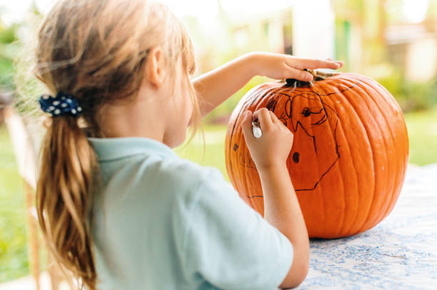 istock Child decorates a pumpkin outdoors for Halloween 1273123937