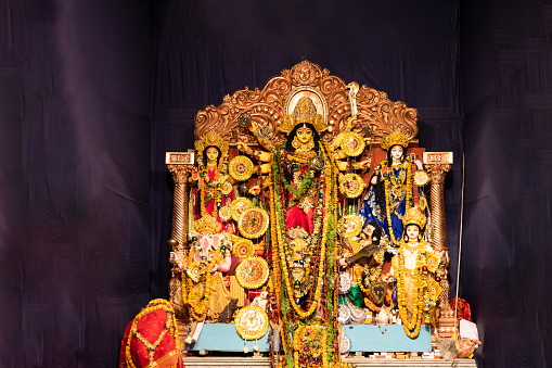 An Idol of Hindu goddess Durga placed in a temporary shed made out of canvas and bamboo, and is decorated with colorful cloths called as Pandal for worship, The deity made out of clay is adorned with decorative work. Durga Puja ,also called Durgotsava  is an annual Hindu festival originating in the Indian subcontinent, mainly in West Bengal and Kolkata which reveres and pays homage to the Hindu goddess, Durga.