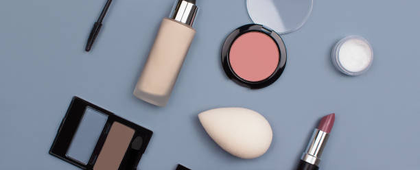 istock Makeup professional products flat lay on blue background top view. Composition with foundation, eyeshadows, blusher, sponge, mascara, lipstick. Organic, bio, natural cosmetic concept. Stock photo 1273155718