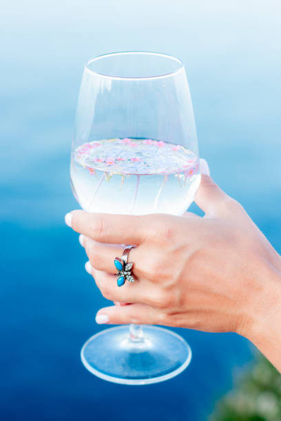 Glass with flowers and hand.