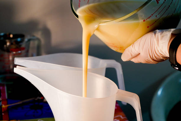 istock Gloved hand with watch pouring white liquid from glass jar into a white plastic spout jar 1273168074