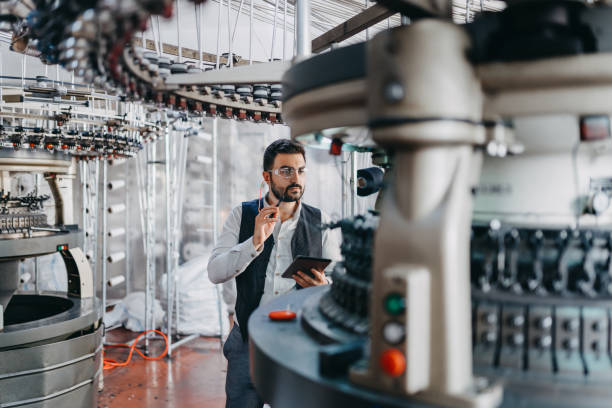 small business owner checking the machines performance - textile textile industry warehouse store imagens e fotografias de stock