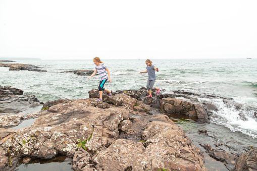 Two young girls (sisters) exploring the shoreline of Lake Superior in northern Minnesota USA. Taken on a foggy day near Two Harbors.