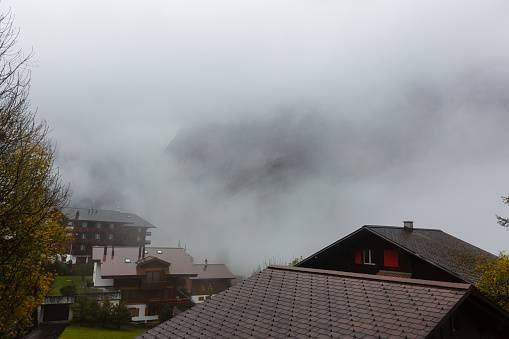 Rural houses chalets in the Swiss Alps against a dark autumn cloudy sky