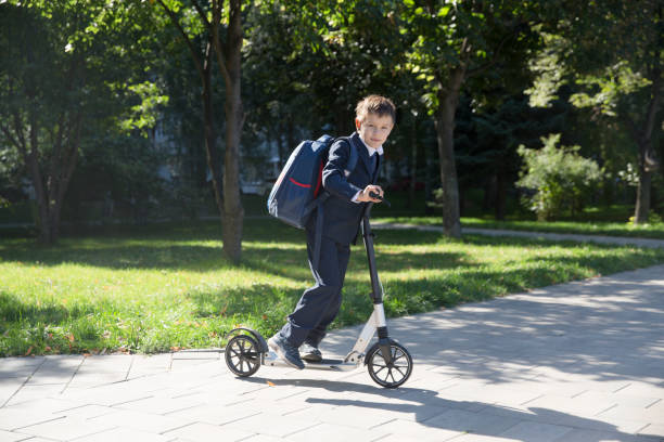 istock Schoolboy with backpack goes on a scooter to school 1273194393