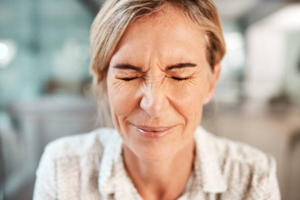 Dealing with a bit of tension Shot of a mature woman closing her eyes in pain grimacing stock pictures, royalty-free photos & images