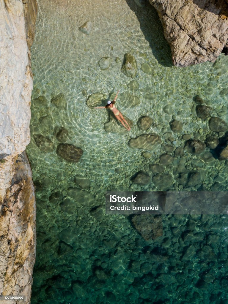 Woman floating on clear sea from above Beach Stock Photo