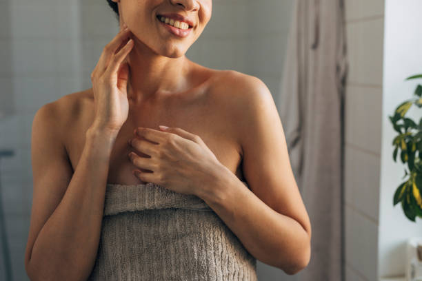 Beautiful African American Woman Wrapped in a Towel after Having a Shower Morning in the bathroom: a pretty young woman getting ready for a new day in her bathroom. body care shower stock pictures, royalty-free photos & images