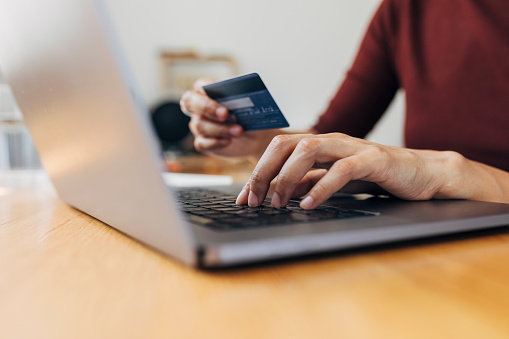 E-banking: hands of an unrecognizable woman placing an online order by using her debit card.