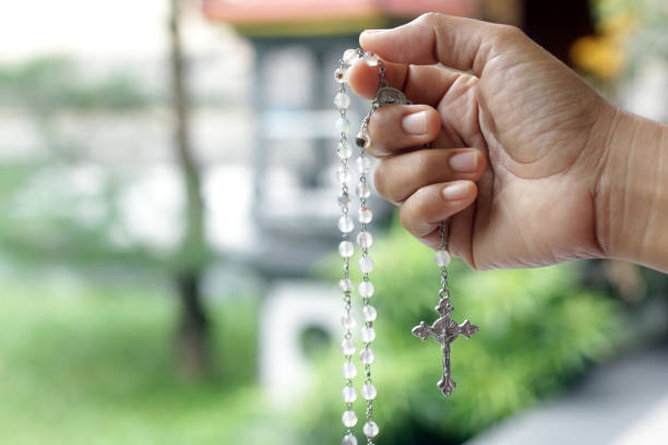 Praying rosary concept. With hand holding rosary beads with Jesus Christ holy cross crucifix. stock photo