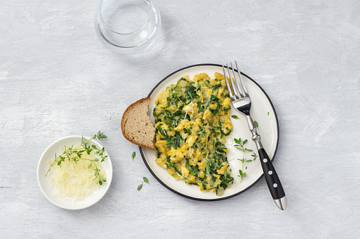 Scrumble eggs with kale and cheese on a light gray background, top view. delicious homemade breakfast