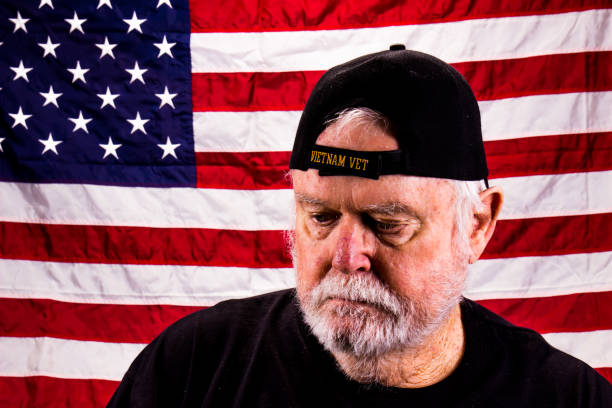 istock Vietnam Vet Looking Down While In Front Of American Flag 1273204056