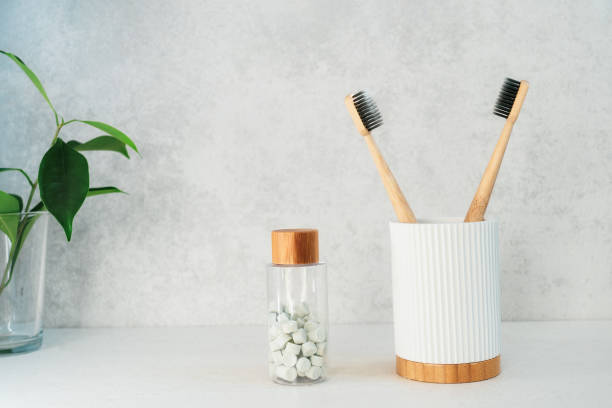istock Zero waste bathroom items. Bamboo toothbrushes in recycling material holder, natural mouthwashing tabs and fresh green plants in glass. Oral care essentials. Eco-friendly home. Minimalism. Copy space. 1273206233