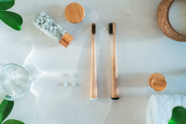 istock Top view zero waste bathroom items. Bamboo toothbrushes, natural mouthwashing tabs, fresh green leaves and glass of water on light background. Oral care essentials. Eco-friendly home. Minimalism. 1273206244
