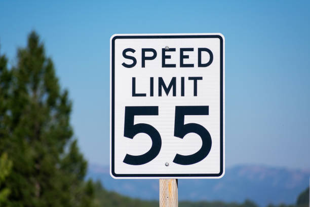 istock Fifty-five mph speed limit sign. Speed zone traffic sign against blurred tree landscape and blue sky 1273208095