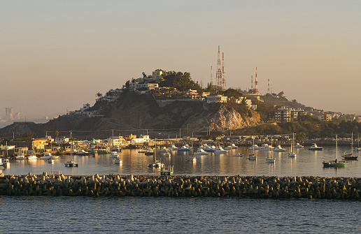 Mazatlan, Mexico - April 23, 2008: Early morning light at entrance from ocean to port. Wave braking protection dam in front of yacht harbor. Hill with antennas in back.