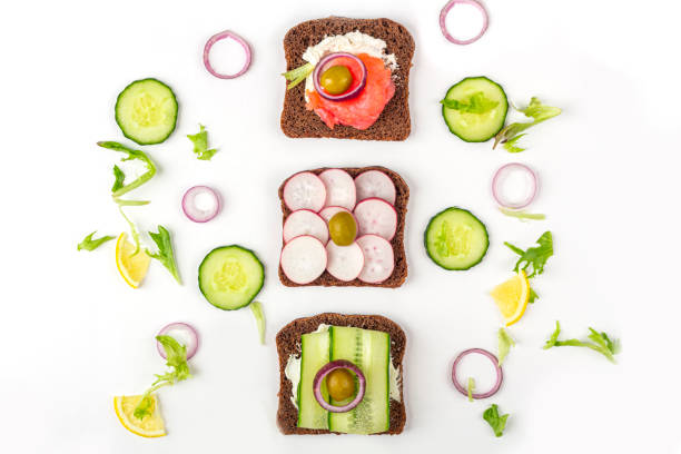 istock Appetizer, open sandwich with different toppings: salmon and vegetables on white background. Traditional Italian or Scandinavian cuisine. Healthy eating. Flat lay, copy space for text 1273212946