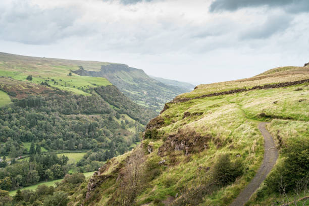 Beautiful scenic valley walking trail at Glenariff, County Antrim, Northern Ireland Scenic view of the walking trail and valley at Glenariff forest in County Antrim, Northern Ireland, in summer with lots of greenery and a cloudy sky glenariff photos stock pictures, royalty-free photos & images