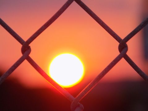 Off-centered sunset from behind chainlink fence in Corpus Christi, Texas USA in September 2020.