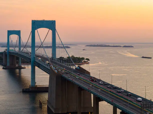 Aerial view of Throgs Neck Bridge over East River connecting Queens and Bronx Boroughs, New York, at sunrise.
