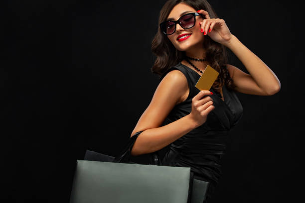 Black friday concept. Shopping woman holding bag and sale card isolated on dark background in holiday. Girl in sunglasses. stock photo