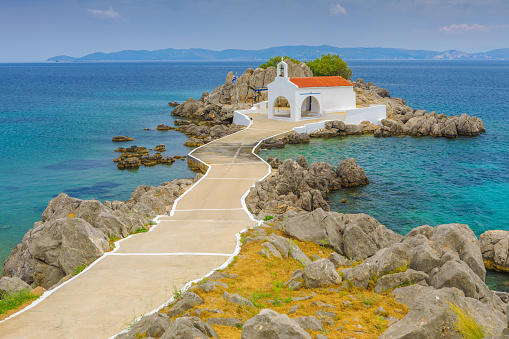 classical white greek church on a small rocky island in Agios Isidoros, Greece