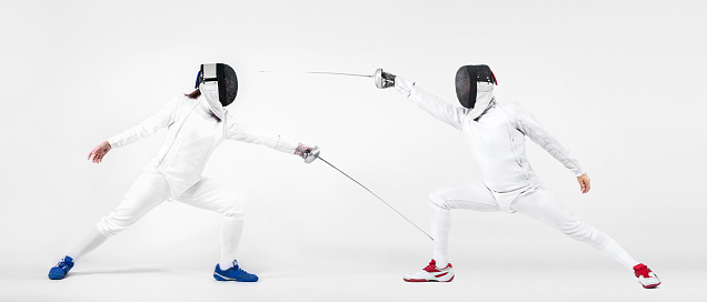 Portrait of Young man fencer wearing mask and white fencing costume and holding the sword in front of her. Isolated on White Background.