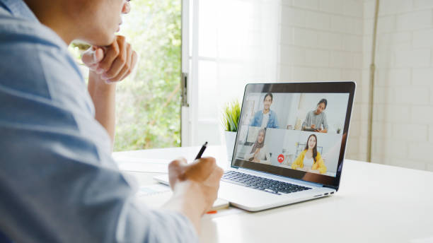 ラップトップを使用した若いアジアのビジネスマンは、リビングルームで自宅で仕事をしながら、ビデオ通話会議で計画について同僚に話します。 - internet dating dating togetherness internet ストックフォトと画像
