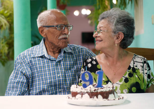 Elder couple celebrating man's 91st birthday Elder couple with a cake on a table and the number 91 on the cake 90 plus years photos stock pictures, royalty-free photos & images